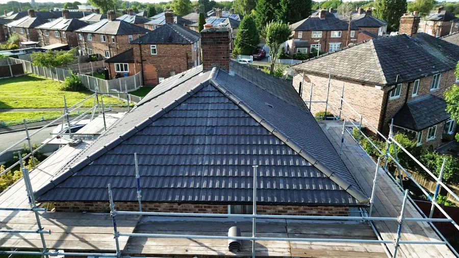 Finished grey tiled hip roof on a bungalow, scaffold still up, seen from above
